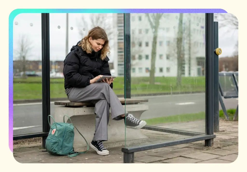 A woman using a tablet at a bus stop